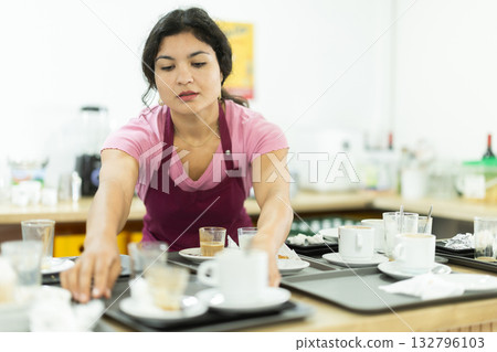Waitress taking away dirty dish in cafeteria 132796103