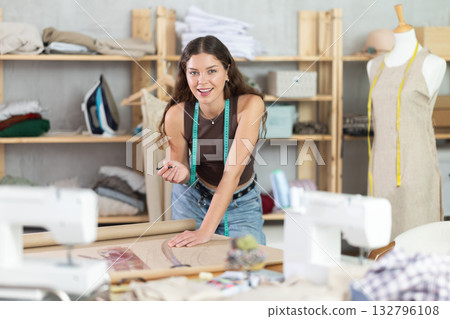 Woman tailor drawing on brown paper in workshop 132796108
