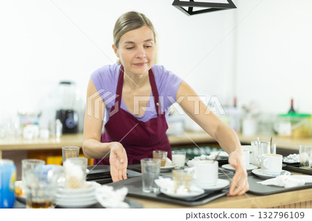 Cafe waitress with a tray of dirty dishes in cafe interior 132796109