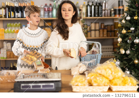 Mother and her son choose different products together for Christmas celebration in grocery supermarket 132796111