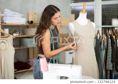 Young female dressmaker working with mannequin in sewing workshop Young female dressmaker working with mannequin in sewing workshop 132796124