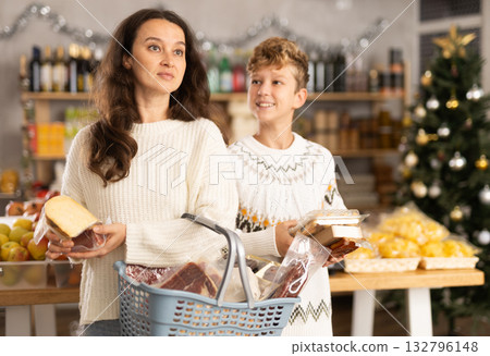 Adolescence boy with mother choose consider snacks in shop on eve of New Year Adolescence boy with mother choose consider snacks in shop on eve of New Year 132796148