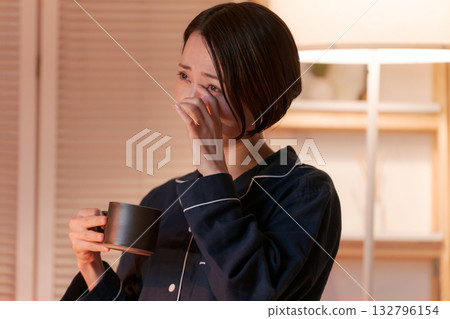 一位穿著睡衣的女士在房間裡放鬆地看電視。 一位穿著睡衣的女士在房間裡放鬆地看電視。 132796154