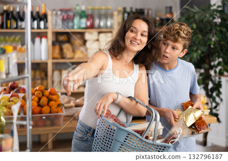 Adolescence boy with mother choose consider snacks in shop Adolescence boy with mother choose consider snacks in shop 132796187