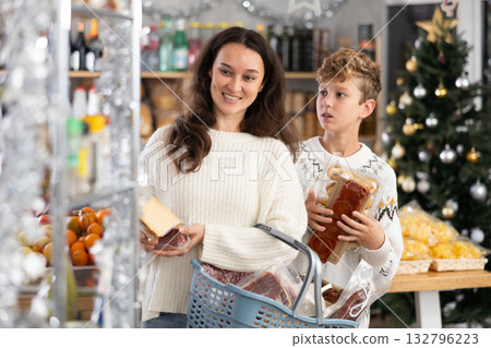 Adolescence boy with mother choose consider snacks in shop on eve of New Year 132796223