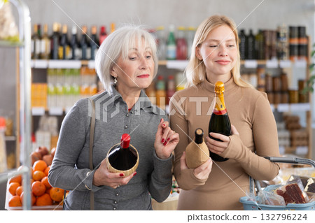 Shopping in produce supermarket - two female buyer makes choice bottle of wine 132796224