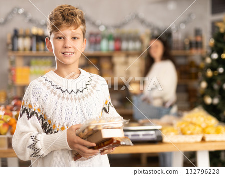 Teenage boy choosing and buying different candies and sweets for Christmas celebration Teenage boy choosing and buying different candies and sweets for Christmas celebration 132796228