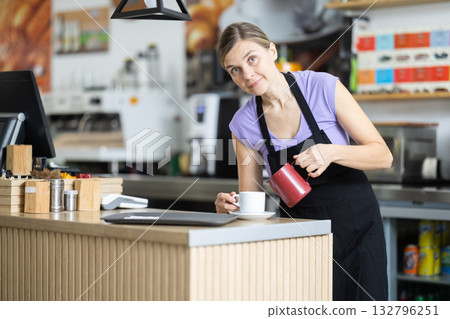 Young female barista pouring coffee into cup at counter Young female barista pouring coffee into cup at counter 132796251