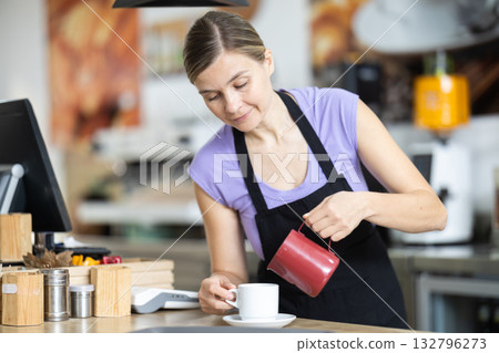 Female cafe employee pours coffee for cafe customers Female cafe employee pours coffee for cafe customers 132796273