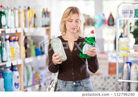 Focused young Woman choosing dishwashing liquid on supermarket shelf Focused young Woman choosing dishwashing liquid on supermarket shelf 132796280