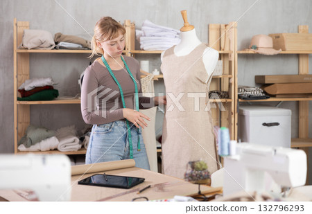 Young female dressmaker working with mannequin in sewing workshop Young female dressmaker working with mannequin in sewing workshop 132796293