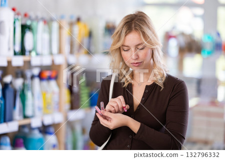 Beautiful stylish young woman choosing lipstick and trying samples in cosmetics department of hypermarket Beautiful stylish young woman choosing lipstick and trying samples in cosmetics department of hypermarket 132796332