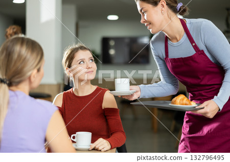 Friendly waitress brought croissants and coffee to female customers 132796495