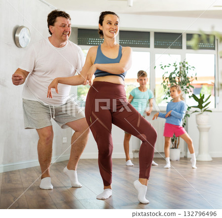 Happy middle-aged man and woman practicing dance in pairs together with their children 132796496