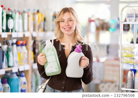 Girl housewife in household store examines goods, chooses liquid detergent Girl housewife in household store examines goods, chooses liquid detergent 132796506