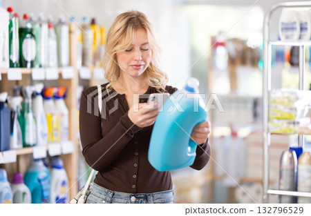 Before making purchase, girl buyer scan QR code on packaging of liquid detergent Before making purchase, girl buyer scan QR code on packaging of liquid detergent 132796529