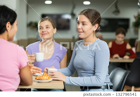 Three girlfriend chatting over coffee and croissant in cafeteria Three girlfriend chatting over coffee and croissant in cafeteria 132796541