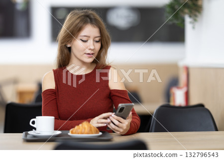 Young woman with phone in cafe 132796543