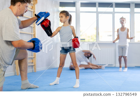 Girl hitting the focus mitts held by his boxing father 132796549