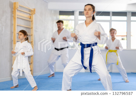 Family with children in kimono trying new martial moves at karate class Family with children in kimono trying new martial moves at karate class 132796587