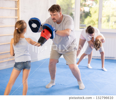 Girl hitting the focus mitts held by his boxing father Girl hitting the focus mitts held by his boxing father 132796610