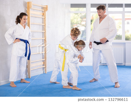 Judo or jiu jitsu classes - family with two children practicing grabbing and throwing on sports mats Judo or jiu jitsu classes - family with two children practicing grabbing and throwing on sports mats 132796611