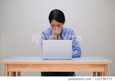 A woman who feels tired eyes from looking at a computer too much A woman who feels tired eyes from looking at a computer too much 132796737