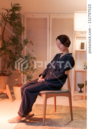 A woman relaxing in a chair at night A woman relaxing in a chair at night 132797020