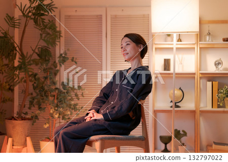 夜晚，一位女士在椅子上放鬆休息。 132797022