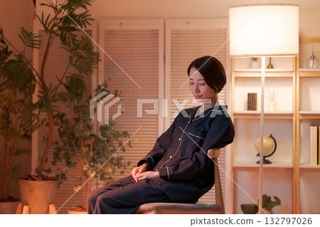 A woman relaxing in a chair at night A woman relaxing in a chair at night 132797026