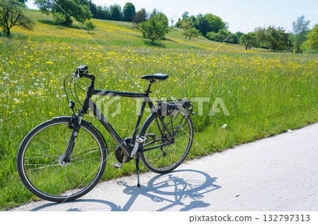 A bicycle parked along a road lined with beautiful rapeseed flower fields A bicycle parked along a road lined with beautiful rapeseed flower fields 132797313