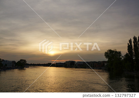 A view of a town in Germany with a river and a beautiful sunset under a cloudy sky 132797327