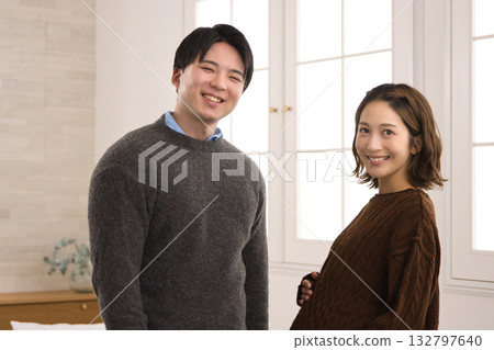 一對年輕夫婦站在窗邊,一名孕婦 一對年輕夫婦站在窗邊,一名孕婦 132797640