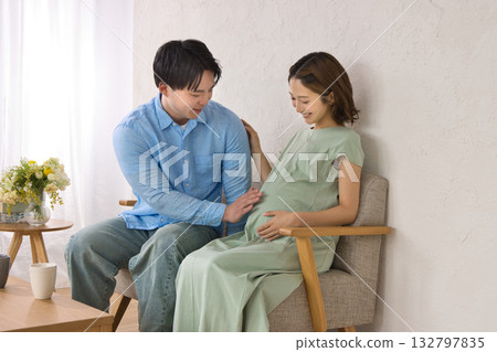 一對年輕夫婦在沙發上休息，孕婦 132797835