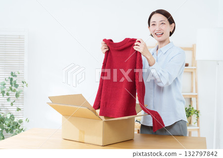 A woman putting clothes into a cardboard box 132797842