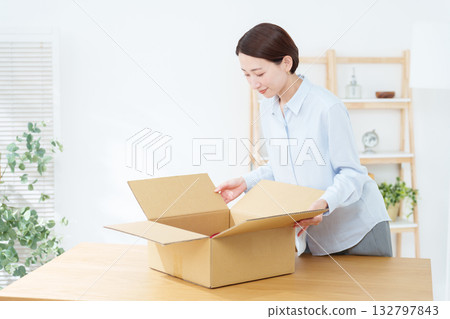 一名女子正在紙箱裡打包 一名女子正在紙箱裡打包 132797843