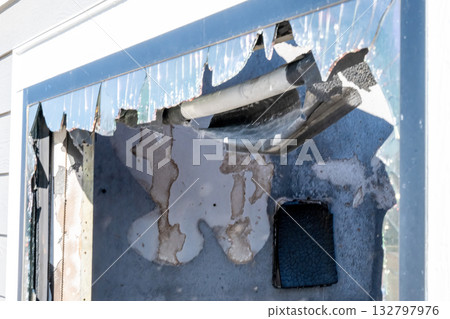 Damage to exterior wall reveals insulation and pipes after fire incident in residential building during daylight hours Damage to exterior wall reveals insulation and pipes after fire incident in residential building during daylight hours 132797976