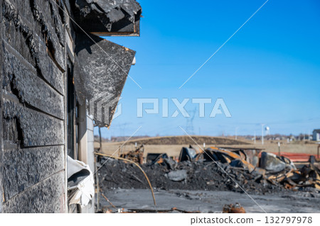 Burnt remains of a building in a rural landscape after a fire on a clear day with power lines in the background Burnt remains of a building in a rural landscape after a fire on a clear day with power lines in the background 132797978
