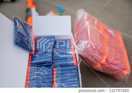 Colorful toy darts and packaging displayed on a surface during a recreational activity Colorful toy darts and packaging displayed on a surface during a recreational activity 132797980