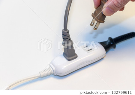 A plug inserted into a power strip A plug inserted into a power strip 132799611