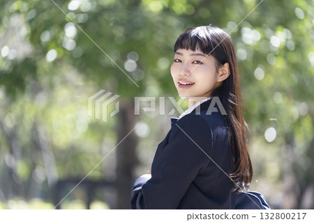一位面帶微笑的女高中生回頭看向鏡頭。 一位面帶微笑的女高中生回頭看向鏡頭。 132800217
