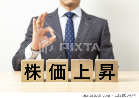 一位商人擺出「OK」的姿勢，旁邊立著一塊寫著「股價上漲」的牌子。 132800474