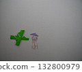 Green origami paper made by a child stuck on the wall 132800979
