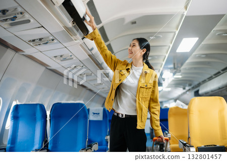 Attractive Asian female passenger of airplane sitting in comfortable seat while working laptop and tablet. Travel in style, work with grace. 132801457