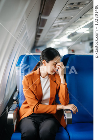 frustrated woman sitting on an airplane with her head in her hands. Asian woman sitting in a seat in airplane 132801486