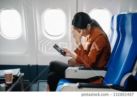 frustrated woman sitting on an airplane with her head in her hands. Asian woman sitting in a seat in airplane frustrated woman sitting on an airplane with her head in her hands. Asian woman sitting in a seat in airplane 132801487