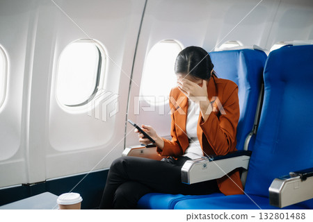 frustrated woman sitting on an airplane with her head in her hands. Asian woman sitting in a seat in airplane 132801488