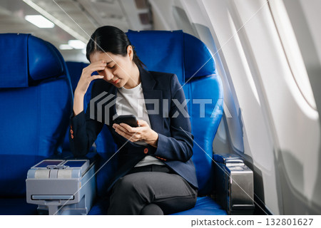 frustrated woman sitting on an airplane with her head in her hands. Asian woman sitting in a seat in airplane frustrated woman sitting on an airplane with her head in her hands. Asian woman sitting in a seat in airplane 132801627