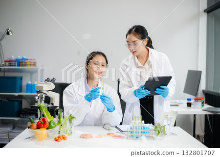 Two Asian scientists in a lab conducting food research using a microscope and lab equipment, showcasing innovation in food science Two Asian scientists in a lab conducting food research using a microscope and lab equipment, showcasing innovation in food science 132801707