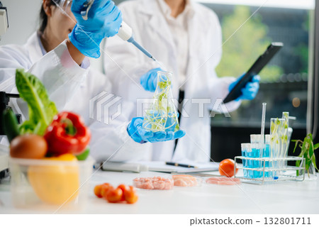 Two Asian scientists in a lab conducting food research using a microscope and lab equipment, showcasing innovation in food science Two Asian scientists in a lab conducting food research using a microscope and lab equipment, showcasing innovation in food science 132801711